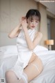 A woman in a white lingerie sitting on a bed.