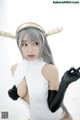 A woman in a white bodysuit and black gloves posing for a picture.