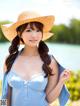 A woman in a blue dress and a straw hat posing for a picture.