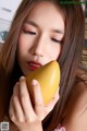 A woman holding a mango in her hand. 