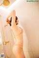 A woman in a tan bikini standing in a shower.