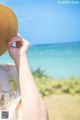 A woman wearing a straw hat looking out at the ocean.