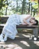 A woman laying on a bench in a park.