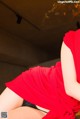 A woman in a red dress sitting on a wooden table.