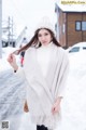 A woman wearing a white sweater and a white hat in the snow.