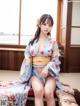 A woman in a blue kimono sitting on a bed.
