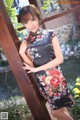 A woman in a black and red floral dress posing for a picture.