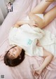 A woman laying on top of a bed wearing a white shirt.