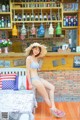 A woman in a bikini sitting on a bench in front of a bar.